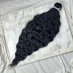 May include: A long, black, wavy hair extension with a white ribbon tied at the top.