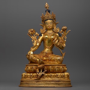 May include: A gold-coloured statue of a seated female deity wearing a crown and elaborate jewellery. The statue is on a base with intricate details.