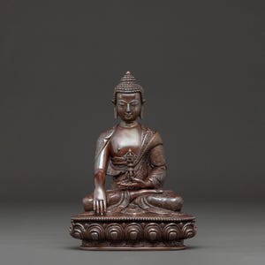 May include: A bronze Buddha statue in a seated meditation pose. The figure has detailed facial features, a serene expression, and ornate clothing. The statue is on a detailed lotus base, with intricate patterns and designs.