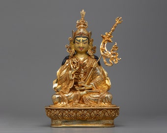May include: A gold-colored statue of a seated figure with a crown and a scepter. The figure is adorned with intricate details and has a serene expression.