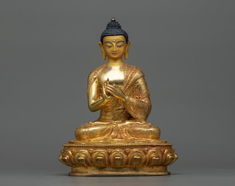 May include: A gold-coloured statue of Buddha sitting in meditation pose. The statue is detailed with intricate carvings and has a serene expression.