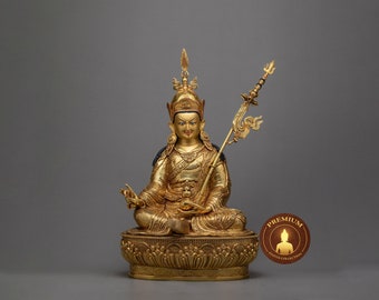 May include: A gold-colored statue of a deity with a crown and a spear, sitting on a lotus throne. The statue is intricately detailed and has a serene expression.
