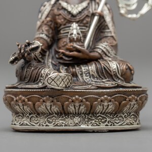 May include: A silver and copper colored statue of a seated figure with a crown and a scepter. The statue is intricately detailed and has a decorative base.