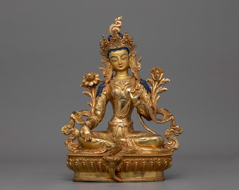 May include: A gold-colored statue of a deity sitting in a meditative pose. The statue is adorned with intricate details and has a blue and gold crown.