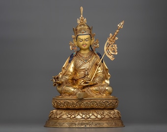 May include: A golden statue of a seated figure with a crown and a scepter. The figure is adorned with intricate details and colorful jewels. The statue is set on a lotus base.