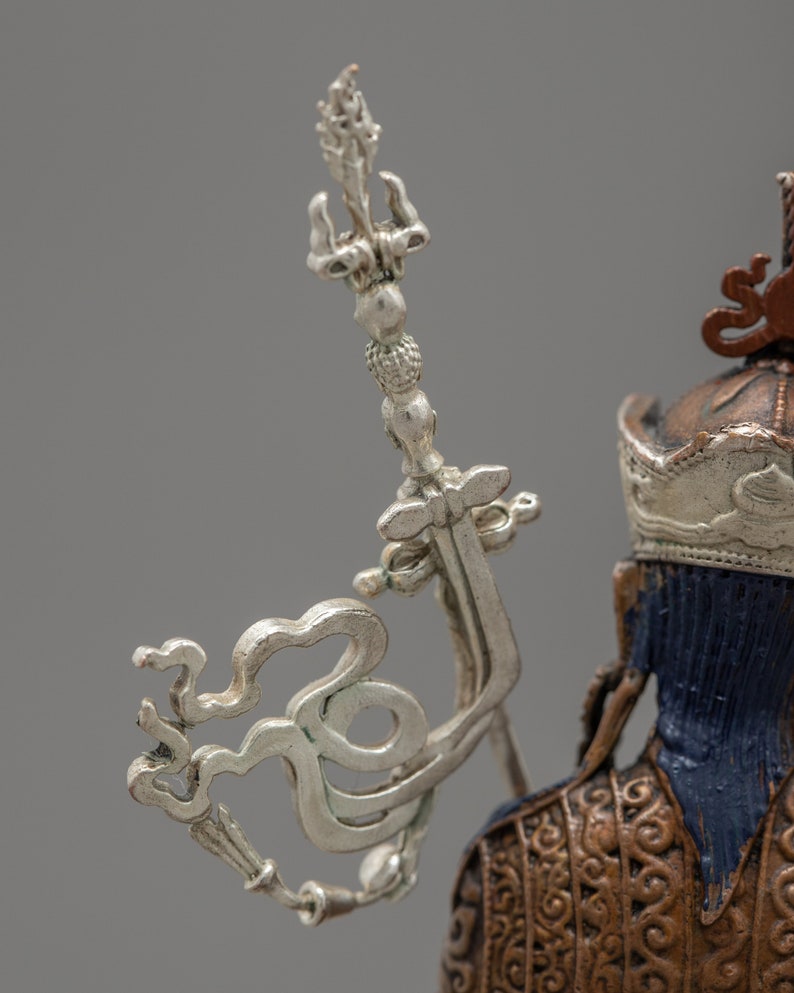 May include: Close-up of a silver and gold statue with a detailed design. The statue has a crown and a silver scepter with a decorative top.