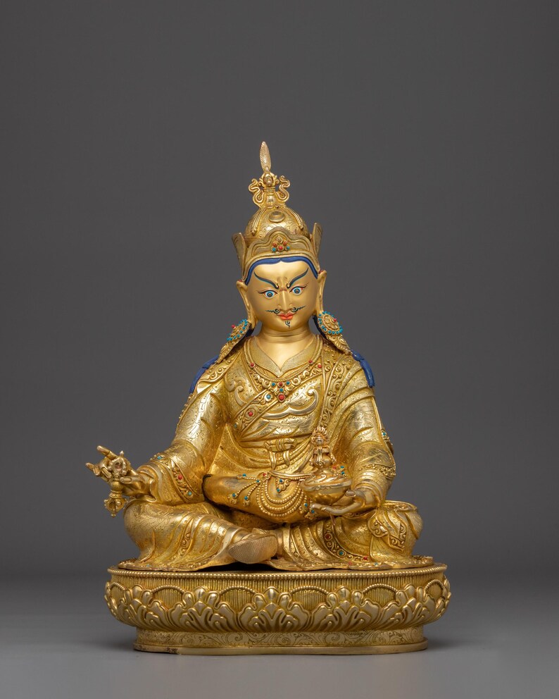 K&ouml;nnte beinhalten: Eine goldene Statue einer sitzenden Figur, geschm&uuml;ckt mit einer detaillierten Krone und Gew&auml;ndern. Die Figur befindet sich in einer meditativen Pose und h&auml;lt Gegenst&auml;nde in ihren H&auml;nden. Die Statue steht auf einem dekorativen Sockel mit aufwendigen Schnitzereien und Details.