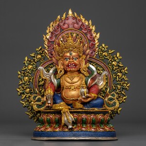 Könnte beinhalten: Eine mehrfarbige Statue einer Gottheit mit grimmigem Ausdruck, die eine goldene Krone und Schmuck trägt. Die Figur sitzt auf einem Lotussockel, hält ein kleines Gefäß in der einen und ein rituelles Objekt in der anderen Hand, umgeben von einem verzierten Heiligenschein.