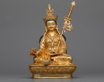 May include: A gold-colored statue of a seated figure with a crown and a scepter. The figure is wearing a robe with intricate details and has a serene expression.