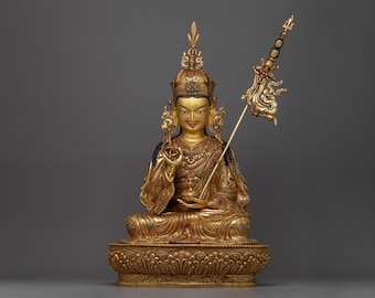 May include: A gold-colored statue of a seated figure with a crown and a scepter. The figure is adorned with intricate details and colorful gemstones. The statue is set on a decorative base.