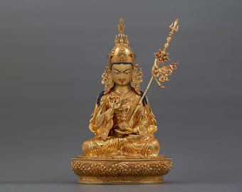May include: A gold-colored statue of a seated figure with a crown and a scepter. The figure is wearing a robe and has a serene expression.