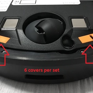 Può includere: Base nera per robot aspirapolvere con due coperture arancioni e la scritta "6 covers per set". La base ha una ruota centrale e due componenti argentati rettangolari.
