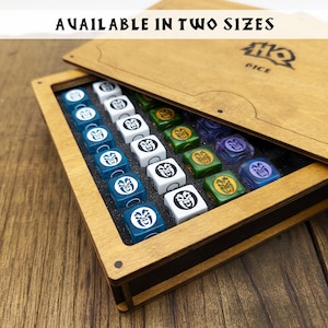 May include: A wooden box with a hinged lid, open to reveal a set of colorful dice with a skull and crossbones design. The box is labeled "HQ DICE" and says "AVAILABLE IN TWO SIZES".