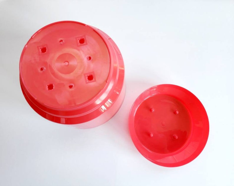 May include: Two red plastic plant pots, one larger than the other, with drainage holes in the bottom.