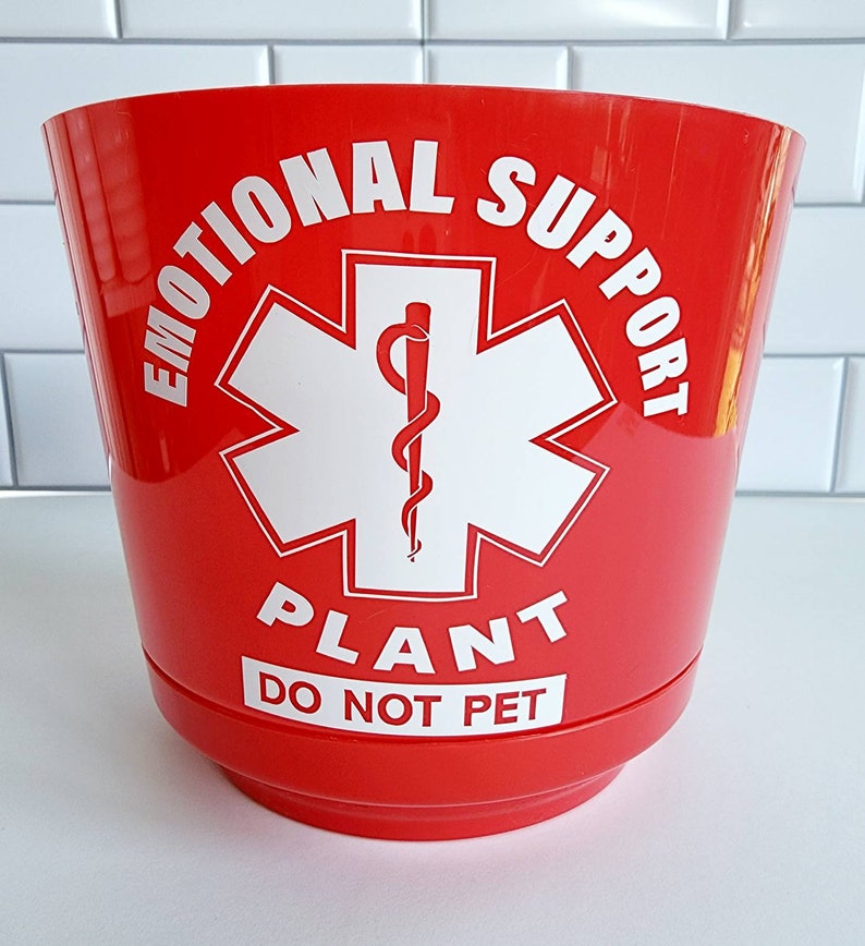 May include: Red plastic planter with a white star of life symbol and the text "Emotional Support Plant Do Not Pet".