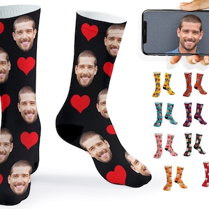 May include: A pair of black socks with a red heart and a repeated pattern of faces. The socks are shown on a white background.