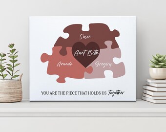May include: A canvas print featuring a puzzle design with four pieces in shades of brown and pink, each with a name. The central piece is a heart shape with the name "Aunt Beth". The text "YOU ARE THE PIECE THAT HOLDS US Together" is at the bottom.