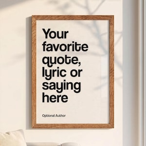 May include: A rectangular wall art print in a medium-toned wooden frame. The print features black sans-serif text on a cream background that reads: Your favorite quote, lyric or saying here, followed by the smaller text: Optional Author.