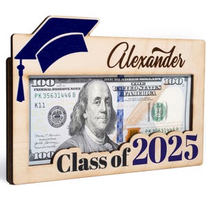 May include: A wooden frame with a graduation cap design, a dollar bill inside, and the text "Alexander Class of 2025".