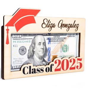May include: A wooden frame with a graduation cap design, a $100 bill inside, and the text "Eliza Gonzalez Class of 2025".