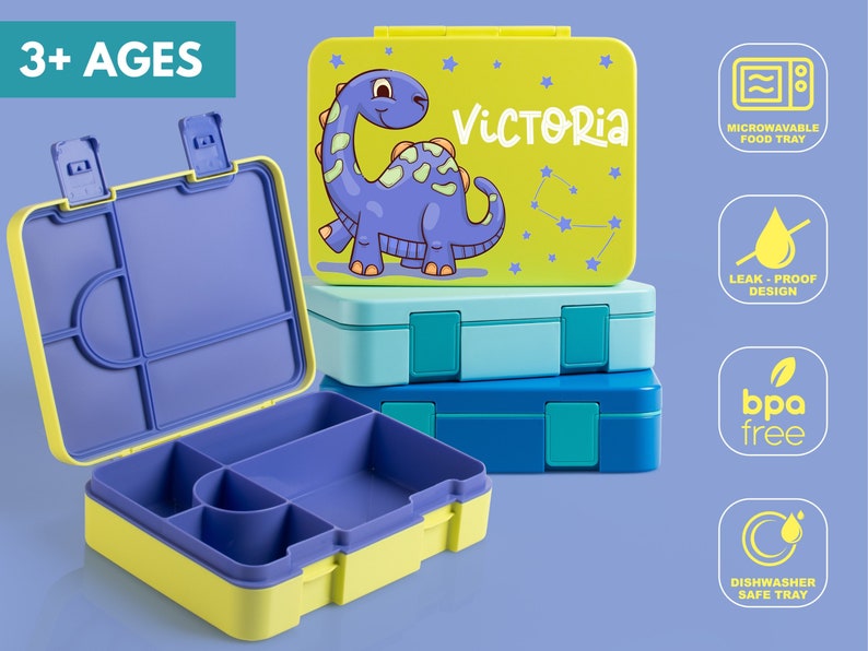 May include: Stack of colorful lunch boxes. The top box is lime green with a purple dinosaur graphic and the name "VICTORIA". The open box is yellow and purple. Features include microwaveable, leak-proof, BPA-free, and dishwasher-safe.