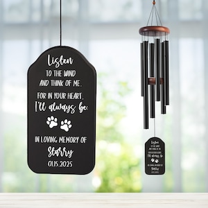 May include: Black wind chimes with a wooden top and a memorial plaque. The plaque reads "Listen to the wind and think of me. For in your heart, I'll always be. In loving memory of Starry 01.15.2025" with paw prints.