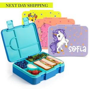 May include: A blue and turquoise lunchbox with compartments, filled with food. Several closed lunchboxes with animal and unicorn designs are in the background. The text "SOFIA" is on one lunchbox.