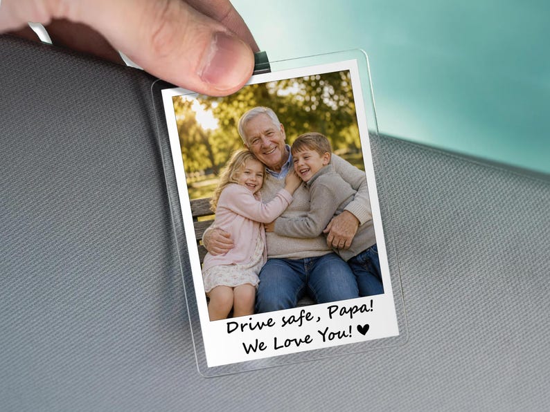 May include: A clear, rectangular photo holder with a family photo. The photo shows a grandfather hugging two grandchildren. Text at the bottom reads "Drive safe, Papa! We Love You!" with a heart symbol.