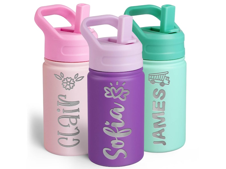 May include: Three cylindrical water bottles with straw lids. The light pink bottle features a flower icon and the name Clair. The purple bottle features a heart icon and the name Sofia. The mint green bottle features a truck icon and the name James.