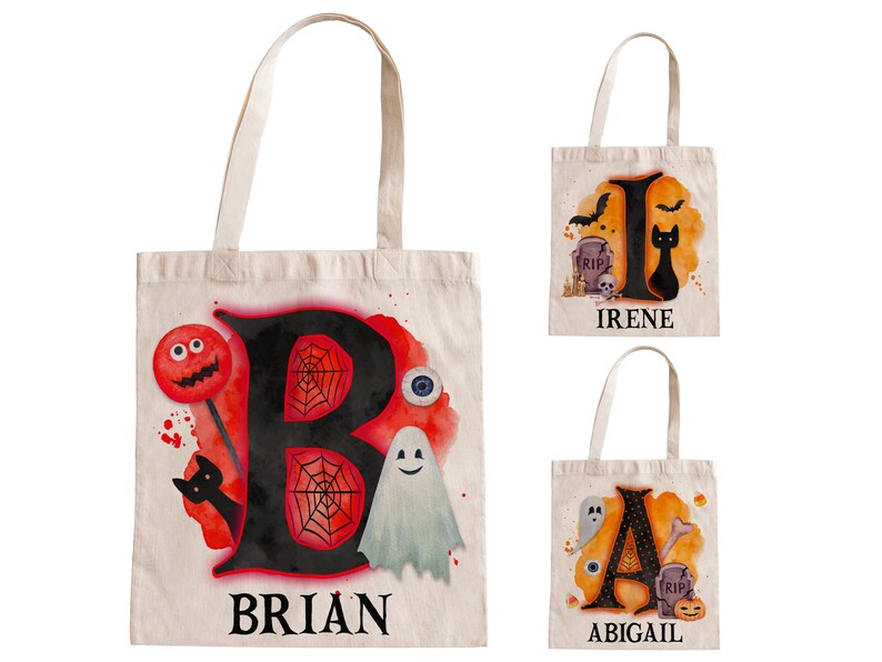 May include: Three Halloween-themed tote bags with personalised names. The bags are made of natural canvas and feature a black letter with a watercolour background and Halloween-themed illustrations. The bags are labelled "BRIAN", "IRENE", and "ABIGAIL".