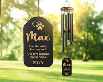 May include: A black memorial wind chime with the name "Max" and a paw print design. The chime includes the text "Feel the wind, hear my soul, Our love remains forever whole 2025". The wind chime is hanging outdoors.