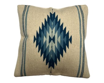 May include: A square throw pillow with a beige background and a blue geometric pattern in the center. The pillow has a blue border with a repeating pattern.