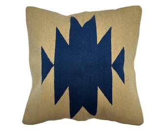 May include: A tan throw pillow with a navy blue geometric pattern. The pattern is a series of triangles and rectangles.