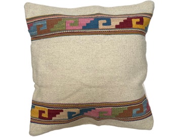 Puede incluir: Una almohada blanca con un borde de patrón geométrico colorido. El patrón presenta colores rojo, azul, verde, amarillo y rosa.