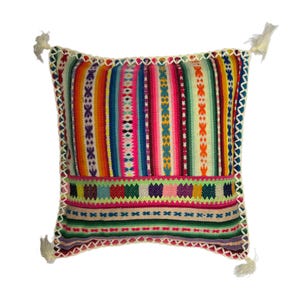 May include: Square decorative pillow with a vibrant, striped pattern in shades of red, orange, yellow, green, blue, and pink. The pillow has a white crocheted border and tassels at each corner. The design includes geometric and floral motifs.
