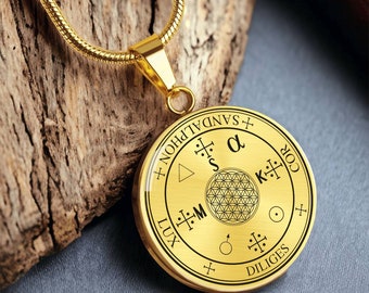 May include: Gold pendant necklace with a round, gold-toned charm featuring a geometric design and the words "SANDALPHON", "LUX", "DILIGES", "COR", "K", "S", "M", and "α".