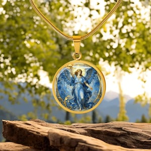 K&ouml;nnte beinhalten: Vergoldete Halskette mit Anh&auml;nger, die einen runden Anh&auml;nger mit einer Illustration eines himmlischen Engels in Blau- und Goldt&ouml;nen zeigt. Der Engel ist mit Fl&uuml;geln und einem Schwert dargestellt. Die Halskette hat eine zarte Kette.