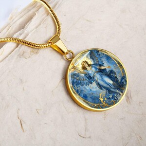K&ouml;nnte beinhalten: Goldfarbene Halskette mit rundem Anh&auml;nger, der einen Engel zeigt. Der Anh&auml;nger zeigt einen Engel in Blaut&ouml;nen mit goldenen Details, vor einem blauen Hintergrund. Die Halskette hat eine goldene Kette.