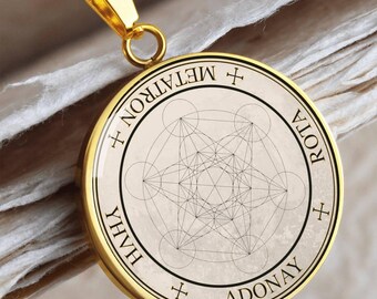 May include: Gold-colored pendant necklace featuring a circular pendant with a cream-colored background. The pendant has a geometric design with the words "METATRON", "ROTA", "ADONAY", and "YHWH" around the edge. The necklace chain is also gold.