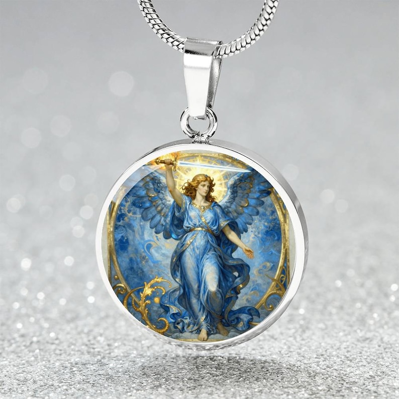 K&ouml;nnte beinhalten: Eine silberne Halskette mit Anh&auml;nger, die einen runden Charm mit einer Engel-Illustration zeigt. Der Engel tr&auml;gt ein blaues Gewand und h&auml;lt ein Schwert. Der Charm hat einen goldenen Rand und h&auml;ngt an einer silbernen Kette.