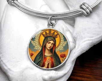 May include: A silver-toned bangle bracelet with a round pendant. The pendant features a religious image of a woman with a halo, crown, and folded hands. The image is set against a backdrop of wings, roses, and a blue sky.