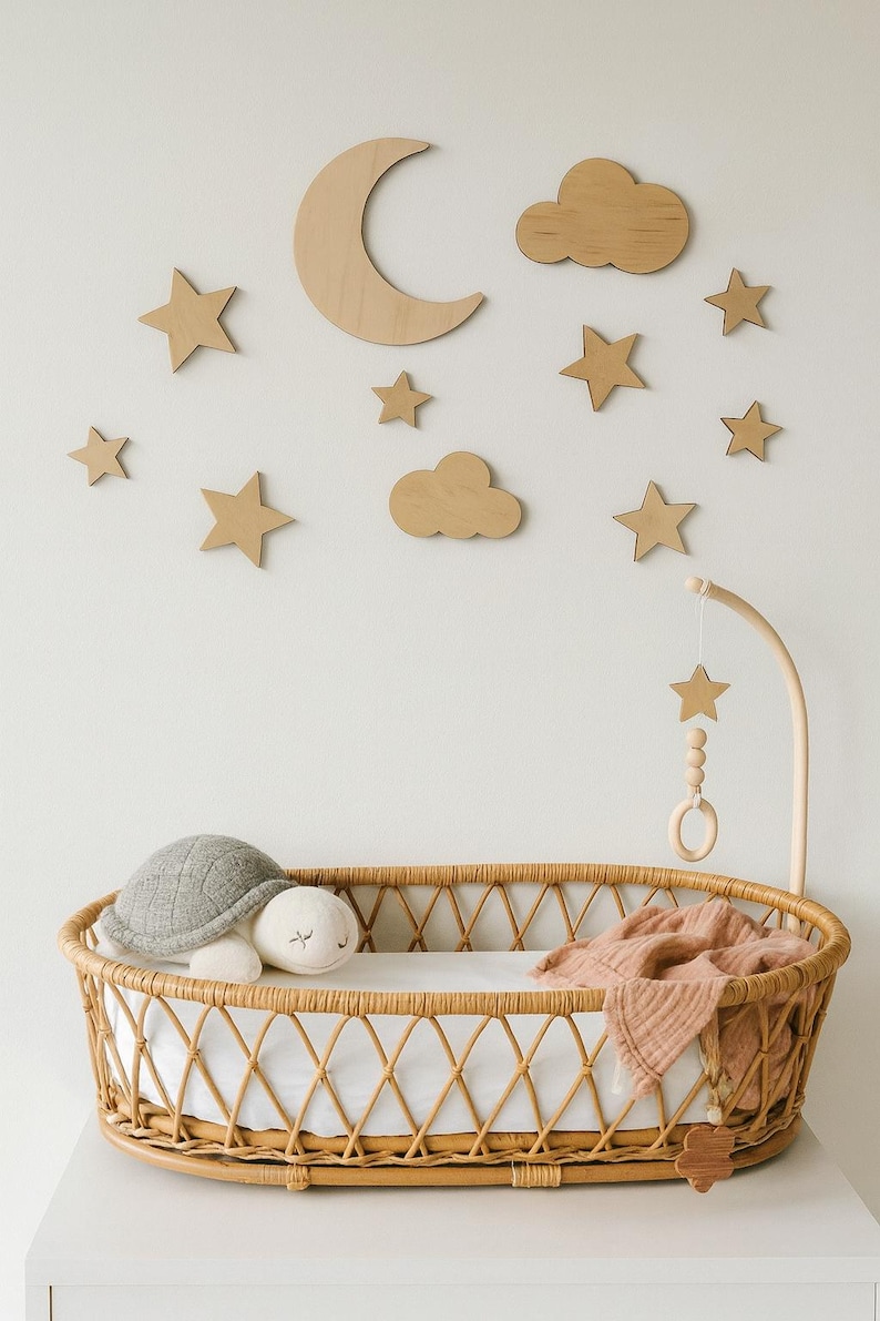 May include: A nursery scene featuring a wicker bassinet with a white sheet, a gray turtle plush, and a white plush toy. Wooden stars, clouds, and a crescent moon decorate the wall. A wooden mobile hangs above the bassinet.