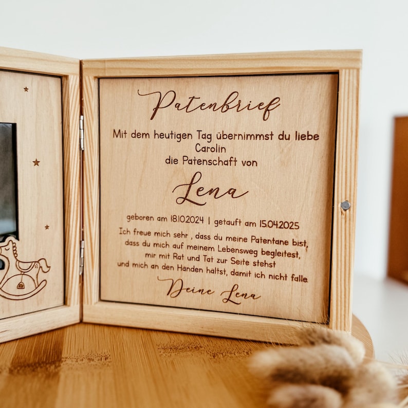 May include: A wooden box with a photo frame and a message inside. The message reads "Patenbrief" and includes the text "Mit dem heutigen Tag &uuml;bernimmst du liebe Carolin die Patenschaft von Lena geboren am 18102024 | getauft am 15.04.2025 Ich freue mich sehr, dass du meine Patentane bist, dass du mich auf meinem Lebensweg begleitest, mir mit Rat und Tat zur Seite stehst und mich an den Handen haltst, damit ich nicht falle Deine Lena".
