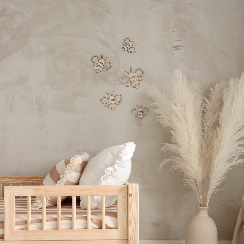 May include: A wooden bed frame with a striped mattress and two pillows. The wall behind the bed is decorated with wooden bee cutouts.