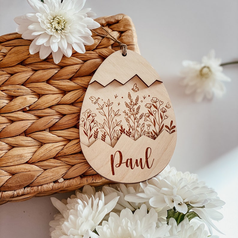 May include: A wooden Easter egg ornament with a floral design and the name "Paul" engraved on it. The ornament is light brown and has a white background.