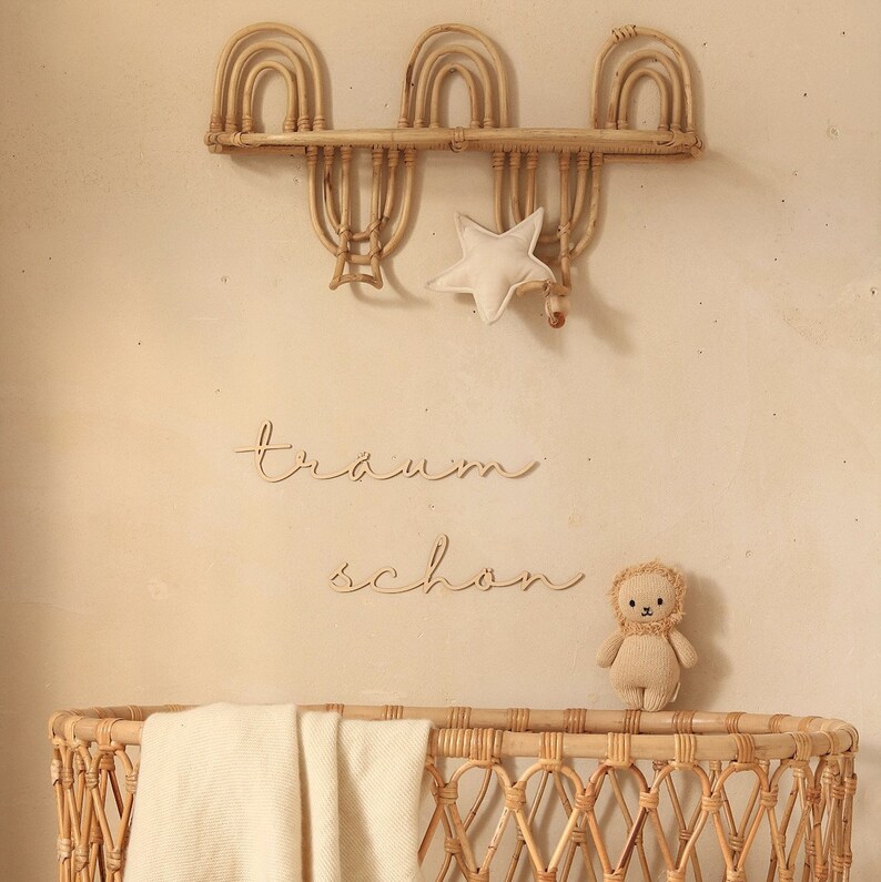 K&ouml;nnte beinhalten: Ein Weidenkorb-Babybett mit einer wei&szlig;en Decke und einem Stofftier-L&ouml;wen. Das Bett ist mit einem Holzschild verziert, auf dem "tr&auml;um sch&ouml;n" steht, und einem sternf&ouml;rmigen Kissen.