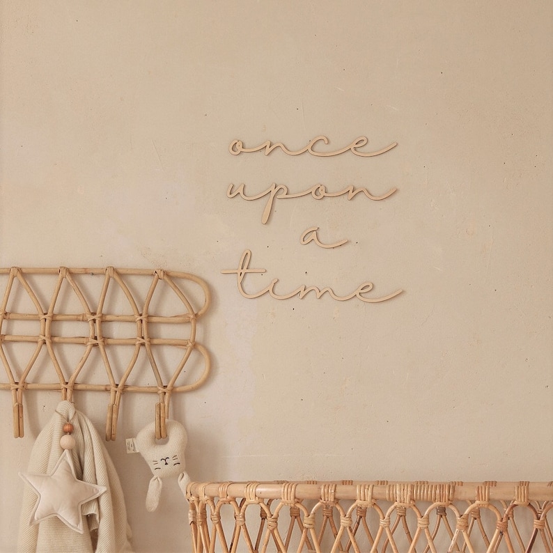 May include: Wooden wall decor with the words "once upon a time" in a cursive font. The decor is mounted on a light beige wall.