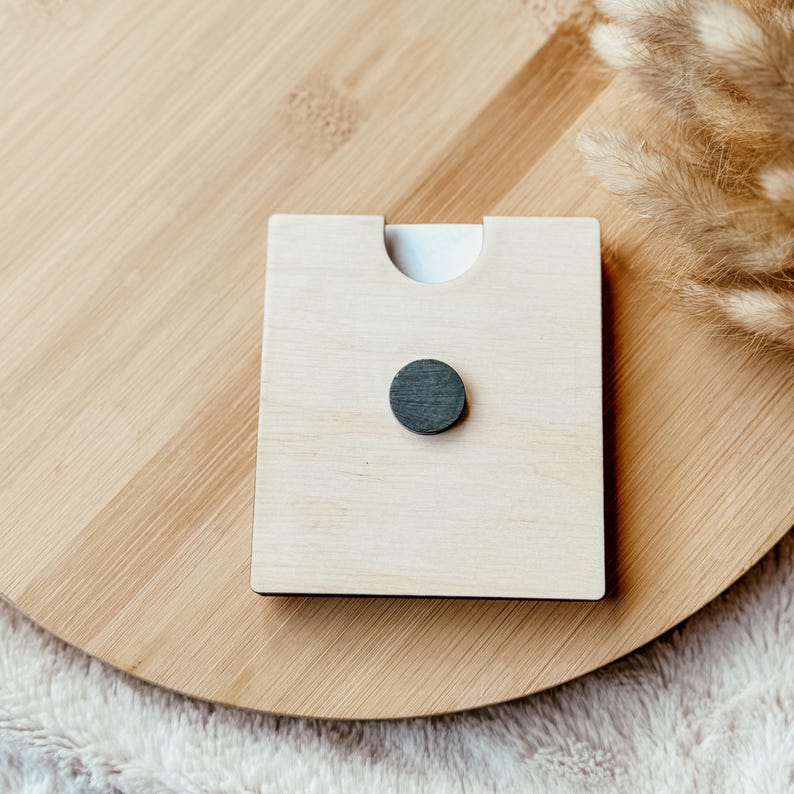 May include: A wooden square with a cutout for a photo or artwork. A small black magnet is attached to the back.