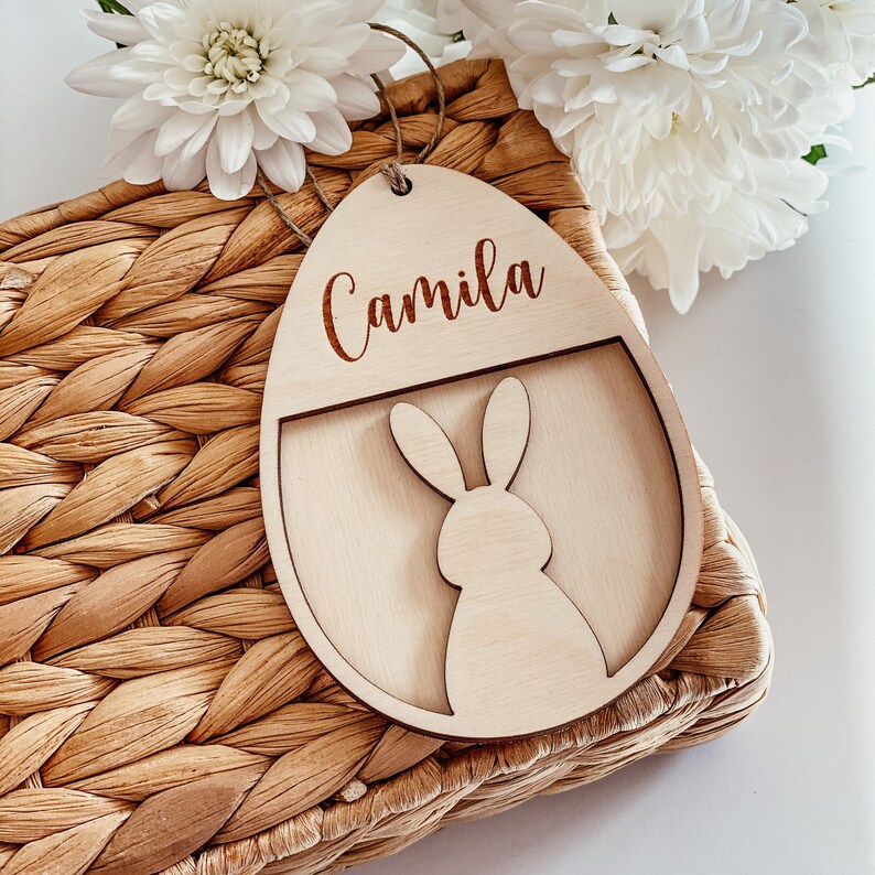 May include: A wooden Easter egg ornament with a bunny cutout and the name "Camila" engraved on the top.