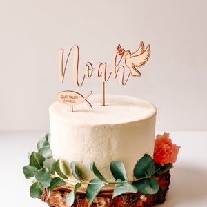 May include: Wooden cake topper with the name Noah, a dove with an olive branch, and a fish with the text "Zur Taufe 23.04.2022".